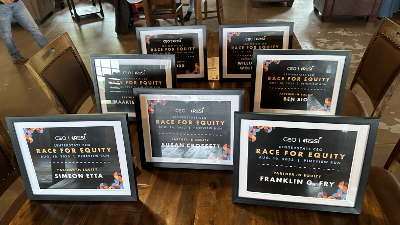 Certificates presented to Race For Equity drivers are displayed on a table.